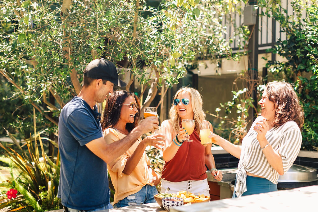 Amber Crocker laughing and toasting drinks with friends outdoors