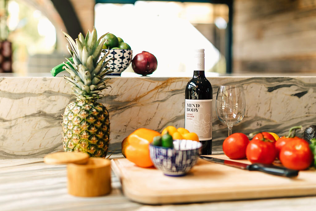 A calm, intentionally arranged kitchen counter with fresh food and wine